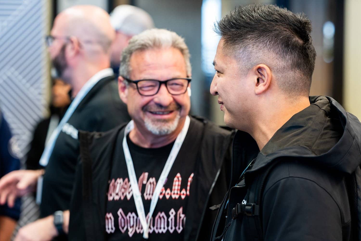 Two men smiling mid-conversation in a full room