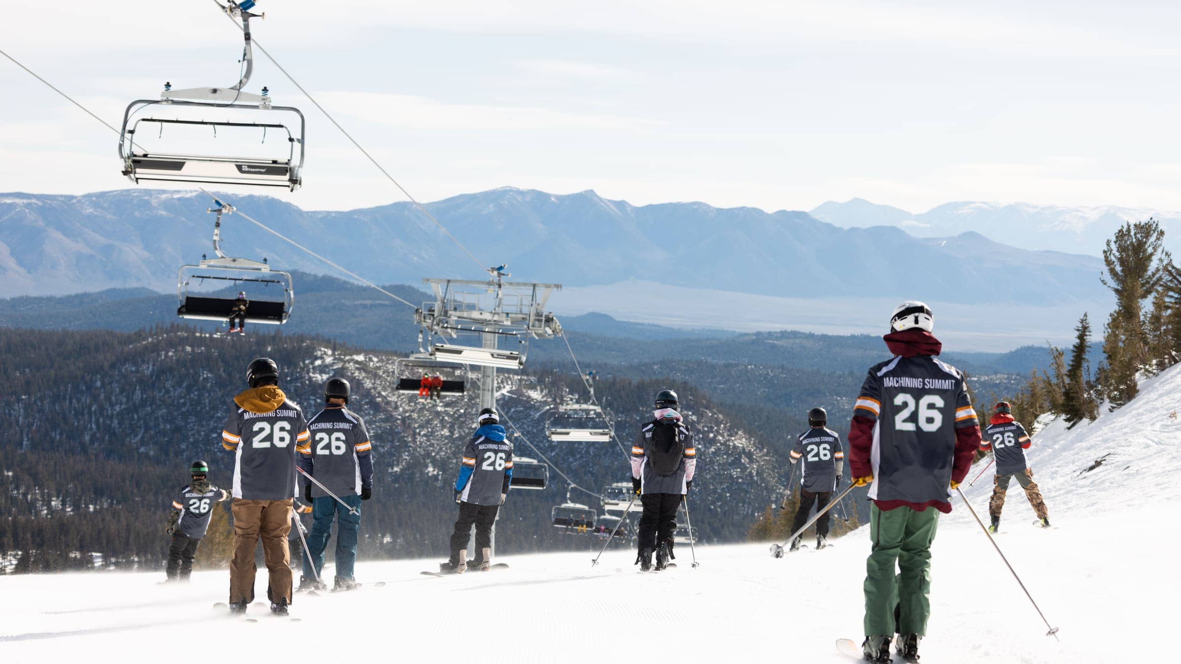 The 2026 Summit's group on the mountain in their 26 jerseys, the lifts and the lake behind