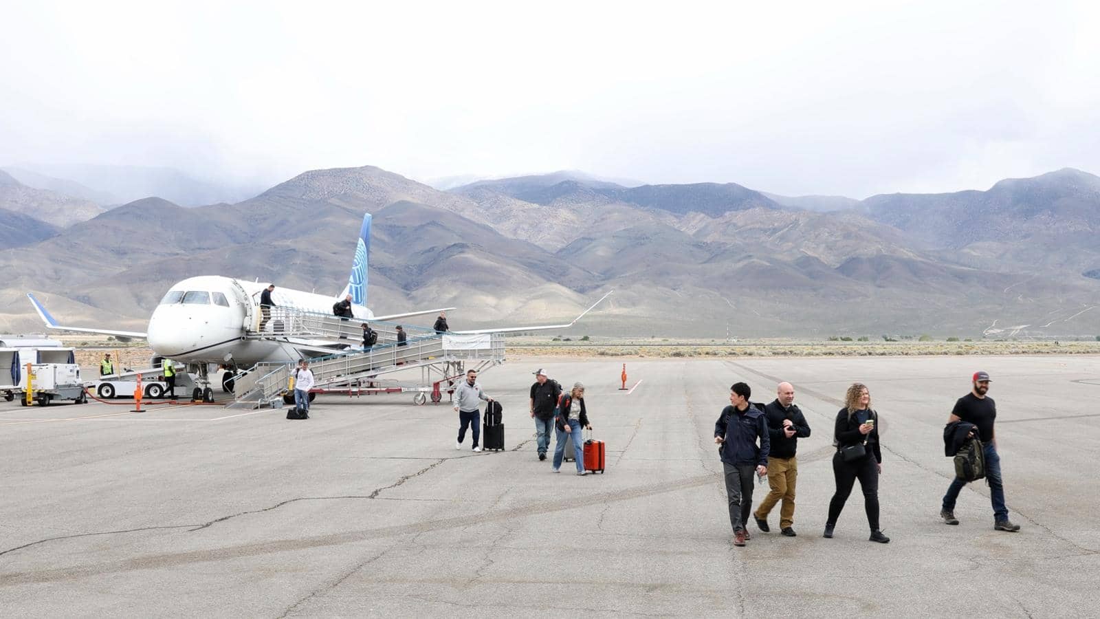 Summit people walking off the United flight in Bishop, the mountains behind